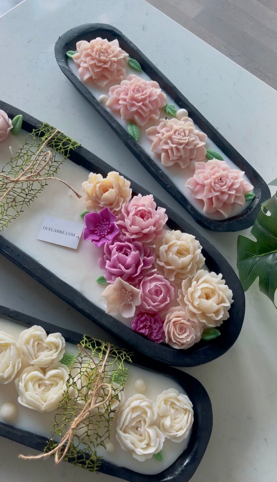 Decorative flower arrangements in black trays on a white surface